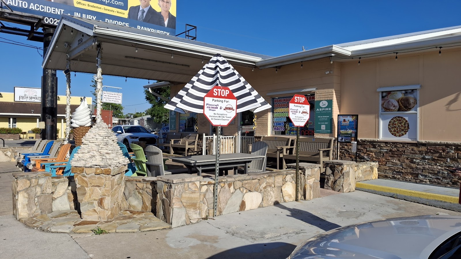 Outdoor seating and umbrellas at Pinecraft Ice Cream Shoppe with the giant ice cream cone statue